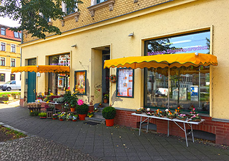 Ladengeschäft des Böhlitzer Blumenparadieses mit gelben Markisen und Blumen vor der Tür